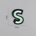 Détail d'un écusson brodé lettre S avec dimensions 4cm sur 3cm sur fond gris - Lettre S