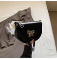 Close-up of black leather saddle bag with silver bow heart buckle and adjustable strap - Black
