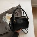 Schwarze Beuteltasche aus Leder mit Hundeanhänger auf grauem Anzug präsentiert - Schwarz