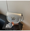 Detailed view of silver saddle bag with metallic bow buckle against a beige wall - Silver