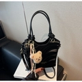 Detail of black wave textured bucket bag with plush bear charm and gold metal hardware - Black with Pendant