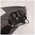Glossy black handbag with silver lock and double handles in a stylish setup - Black