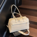 Cream white faux leather travel bag with dual handles on a wooden staircase - Off White