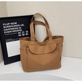 Close-up of brown canvas tote bag featuring front snap-button pocket and side compartment - Caramel color