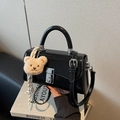Schwarze glänzende Leder-Eimertasche mit Drehverschluss und Plüschbär-Anhänger - Schwarz mit Anhänger
