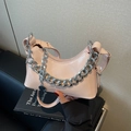 Bolso hobo rosa brillante con cadena plateada gruesa y logo sobre un libro negro - Rosa