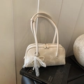 Creamy white pillow shoulder bag with lace bow and pearl charm on a black book - Off White