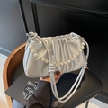Detailed view of silver pleated cloud bag with pearl chain on a black leather chair - Silver