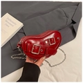 Detail einer tiefroten, glänzenden Herz-Umhängetasche mit silberner Kette - Rot