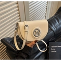 Primer plano detallado del bolso de silla de cuero crema con logo M plateado - Blanco Roto