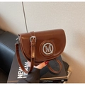Detalle de bolso silla de montar marrón con logo M plateado y correa ajustable fina - Marrón