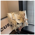 Détail d'un cabas en toile florale avec logo en cuir marron et breloque lapin en tricot - Blanc Cassé avec Charme