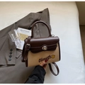 Dettaglio della trama intrecciata e del ricamo timetc sulla borsa in pelle marrone - caffè