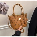 Detailed close-up of brown litchi grain bucket bag with cat logo and logo bag charm - Brown Style (With Charm)