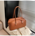 Detail der karamellfarbenen Pillow-Bag aus Leder mit Narbung und Metallschließe im Licht - Gelbbraun