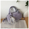 Detail of purple Boston handbag with pearl lace charm and checkered ribbon on wooden surface - Purple