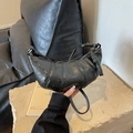 Detalle del bolso croissant negro con asa anudada y cuero de textura agrietada moderna - Negro