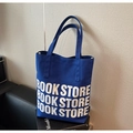 Blue canvas tote bag with white Book Store lettering on a stylish leather sofa - Blue