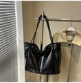 Borsa tote in pelle nera lucida con spalline sottili su sfondo di trench beige - Nero (Senza Ciondolo)