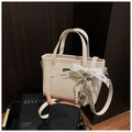 Détail du sac à main beige en cuir avec nœud en dentelle, perles et pendentif cœur - Blanc avec pendentif
