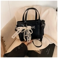 Détail d'un sac à main noir verni avec chaînes de perles et ruban dentelle sur une chaise - Noir Avec Pendentif