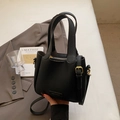 Minimalist black pebble leather bucket bag with gold hardware and removable shoulder strap - Black