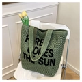 Grüne Strick-Strandtasche mit HERE COMES THE SUN Text-Design auf weißem Stuhl - Grün