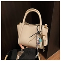 Detail of creamy white pebble leather bucket bag with fashion charms and crossbody strap - Rice White (With Charm)