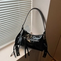 Bolso de hombro negro brillante con flecos largos y cremallera plateada junto a ventana - Negro
