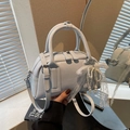 Light blue faux leather Boston handbag with lace bow and pearl charm shown via mirror - Blue