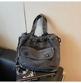Primer plano de bolso de mezclilla lavada con cordón y bolsillo de solapa en sofá de cuero - Negro
