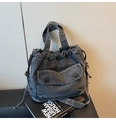 Close-up of washed denim fabric texture with drawstring closure and buttoned pocket - Black
