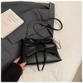 Close-up of black crossbody bag with large bow and silver bead detail on fabric background - Black With Pendant