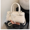 Détail du sac seau crème avec motif crocodile et breloque noeud en dentelle et perles - Blanc avec pendentif