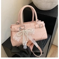 Détail du sac seau rose à motif croco avec nœud en dentelle perlée et boucle argentée - Rose avec pendentif