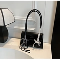 Detail of minimalist black rectangle shoulder bag with lace bow and metal chain charm - Black with Pendant