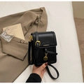 Detail einer schwarzen Lederhandytasche mit goldener Schnalle und Markenlogo - Schwarz