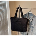 Primer plano de un bolso tote acolchado negro con bolsillo frontal colgado en rack - Negro