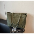 Detalle del bolso tote acolchado verde oliva con costuras diagonales sobre sofá negro - Verde