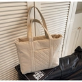 Primer plano del bolso tote acolchado beige mostrando el bolsillo frontal y su textura - Blanco Roto