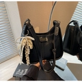 Detail of black glossy faux leather shoulder bag with pearl lace bow charm in mirror - With Pearl Lace Bow Charm / Black