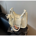 Detail of beige hobo bag showing leather texture with pearl and lace bow charm - With Pearl Lace Bow Charm / Off White