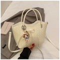 Detail of cream woven bucket bag with metal handle, ribbon bow, and cartoon charm - With Pendant / White