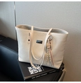 Creamy white woven tote bag with leather straps and colorful tassel on a sofa - With Pendant / White