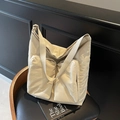 Minimalist cream tote bag with dual front pockets and wide shoulder strap on a chair - Off-white