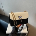 Bolso bandolera negro y beige con dije de gato con gemas púrpuras y cadena dorada - Negro