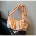 Detail of peach pleated nylon crescent bag with knotted shoulder strap on leather sofa - Peach Pink