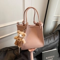 Elegante borsa a mano in pelle rosa loto con manici annodati e un ciondolo a orsetto - Con Ciondolo / Rosa