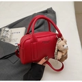 Close-up of red litchi grain bowling bag with a cute plush bear charm and long strap - Wine Red With Bear Charm