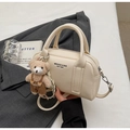 Detail of cream bowling bag with lychee texture and cute bear charm in urban setting - Creamy White (With Bear Pendant)